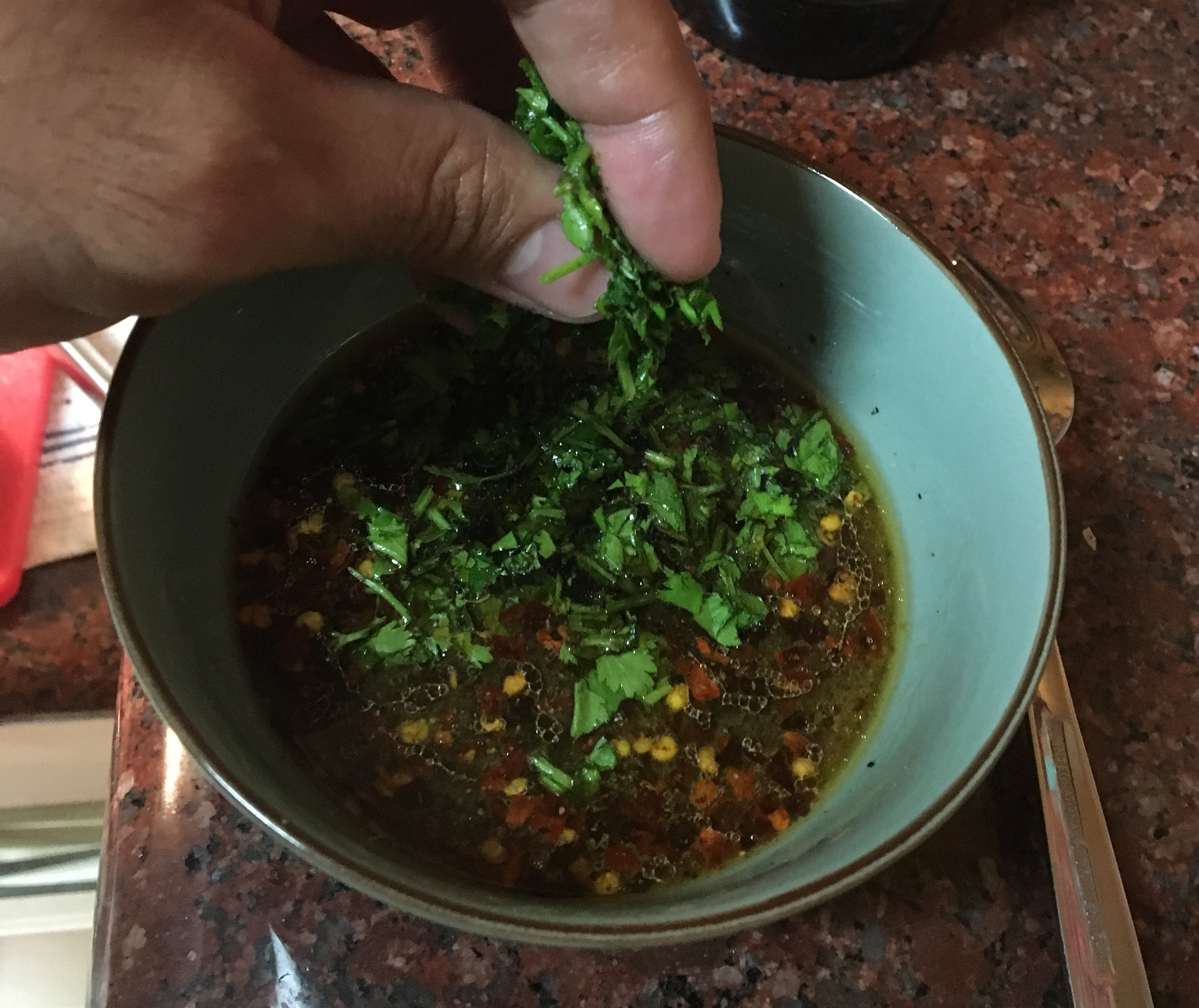 Adding fresh chopped cilantro to a finished bowl of sauce. 